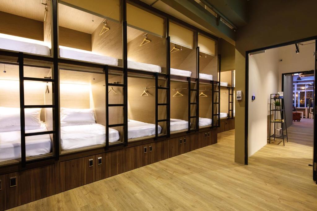 Stacked wooden sleeping capsules with ladders and lockers beneath.
