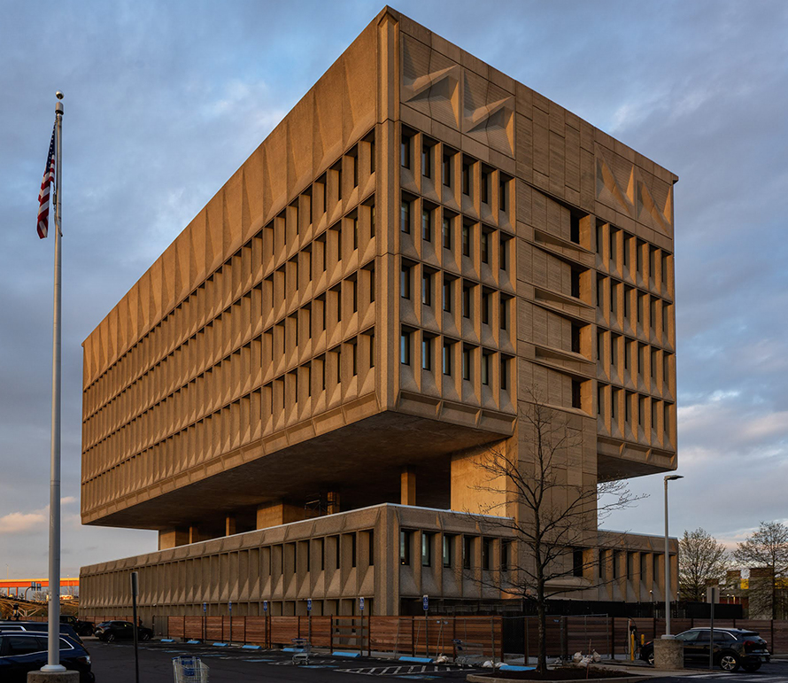 A heavy concrete building with two upper floors carried above a recessed lower level.