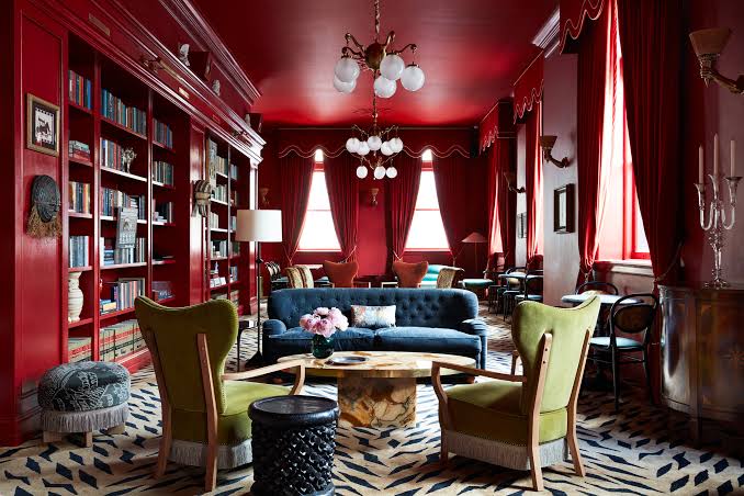A deep red salon with a bookcase, grouped seating and a patterned rug.