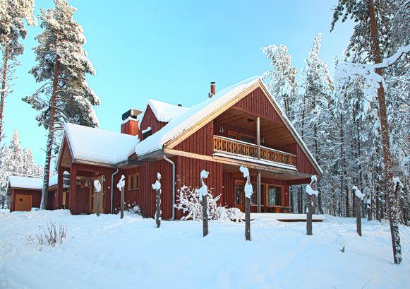 A red timber lodge with snow-covered roofs among pines.