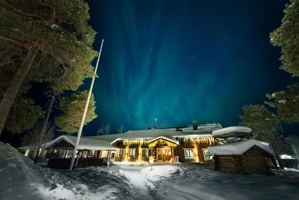 A snow-covered timber lodge among pines under the northern lights.